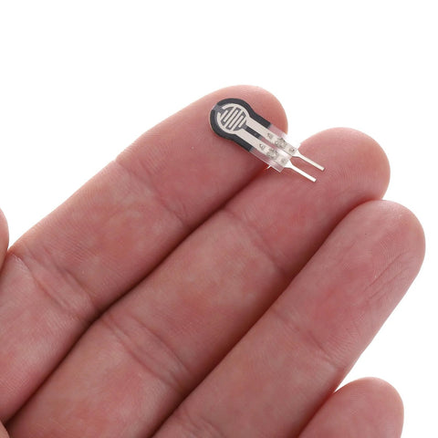 FSR-400sB thin-film force sensor, small round black disk with two silver leads, held on fingertips
