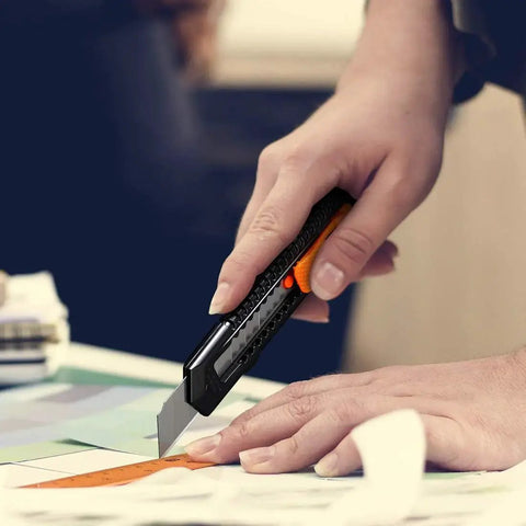 Close-up of a person using a 12 Pack Retractable Utility Knife With 18mm Wide Blade For Cardboard Boxes on a cutting mat.