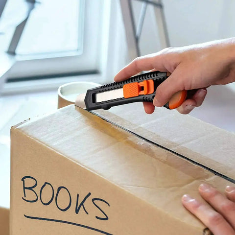 12 Pack Retractable Utility Knife With 18mm Wide Blade For Cardboard Boxes cutting a box labeled 'Books'