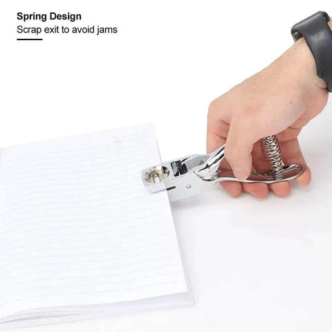 Hand using all metal handheld hole slot puncher for ID cards and paper crafts with 5.4 inch oval punch and spring mechanism on a notebook