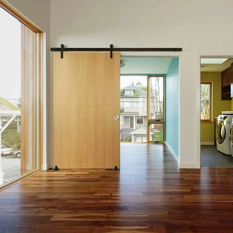 Barn Door Floor Guide Matte Black Metal Floor Mounted Bottom Guide Hardware Adjustable for Sliding Doors Two Pack Durable Carbon Steel With Powder Coated Finish Works With Grooved And Non Grooved Doors installed on a wooden sliding barn door in a modern living room.