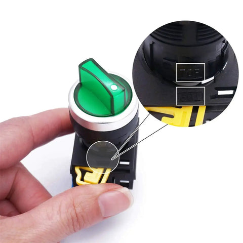 Close-up of a 22mm SPST 1NO two position maintained latching rotary selector switch with green LED indicator held in hand.