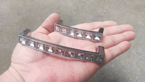 Close-up of two Six Pack U Shape Crystal Glass Drawer Pull Knobs For Cabinets And Dressers with Zinc Alloy Base in a hand.
