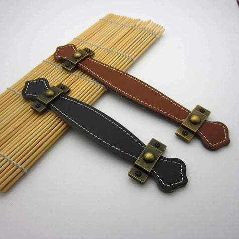 Two Pack Vintage Style PU Leather Cabinet Handles Zinc Alloy Drawer Pulls on bamboo mat, brown and black colors visible
