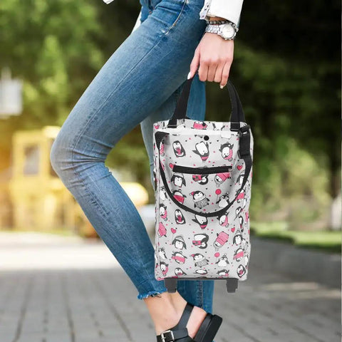 Person holding collapsible trolley bag with wheels for groceries, featuring cartoon pattern, foldable and waterproof Oxford fabric design