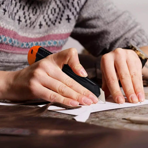 Person cutting cardboard with a 12 Pack Retractable Utility Knife With 18mm Wide Blade For Cardboard Boxes in hand.