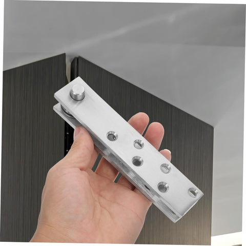 Hand holding Hidden Door Pivot Hinges For Bookcases And Cabinets Heavy Duty Stainless Steel System near a cabinet