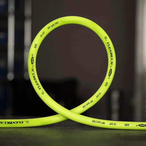 ZillaGreen Air Hose Three Eighth Inch By Fifty Feet With Quarter Inch MNPT Fittings, shown coiled on a dark surface