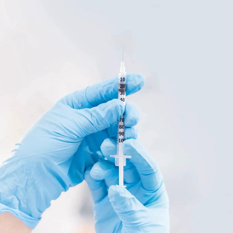 Close-up of One Milliliter Syringe With 30G 8mm Needle, Individually Wrapped Pack Of 30, held by gloved hands.