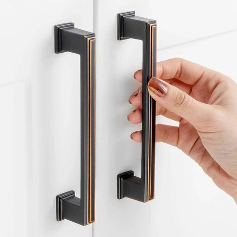 10 Pack 5 Inch Hole Centers Oil Rubbed Bronze Cabinet Pulls being installed on white cabinet doors