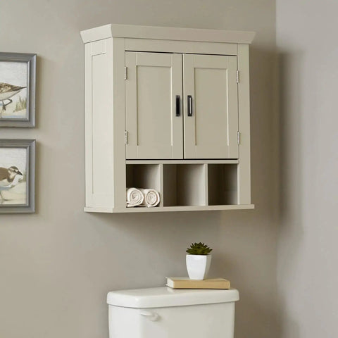 Cream bathroom wall cabinet with two doors and black handles, displayed above a toilet, featuring decorative wall art on the side.