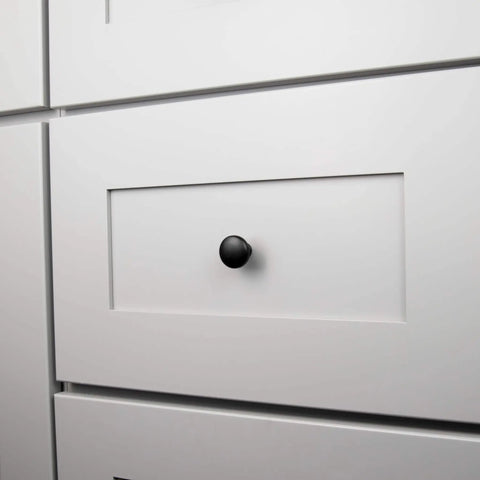 Round Matte Black Kitchen Cabinet Knobs 10 Pack Durable Drawer And Dresser Knobs For Cabinets And Bathroom Drawers One And One Eighth Inch Easy Install Slick Modern Hardware By Hickory Hardware installed on a white cabinet drawer