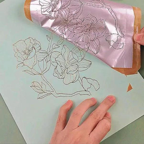 Foil Quill Pen Starter Kit With Four Metal Tips, USB Powered, Gray Finish, Includes Heat Activated Foil Roll 3m By 0.15m For Card Making And Scrapbooking, A Dope, Versatile Hot Foiling Tool For DIY Crafting in use, creating floral design on paper.
