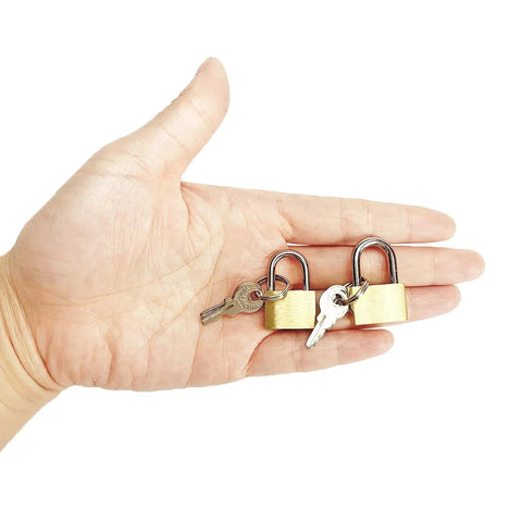 Hand holding two pack small solid brass padlocks with keys 20mm and 25mm mini key locks for luggage backpacks gym lockers jewelry boxes