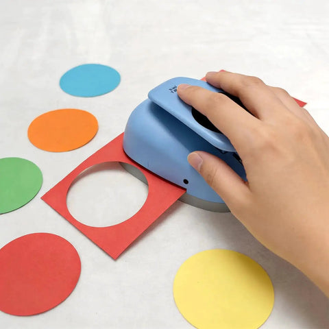 Hand using XL 3 Inch Circle Punch For Paper Crafts And Scrapbooking Easy To Use Spring Action Lever Cutter on colored paper.