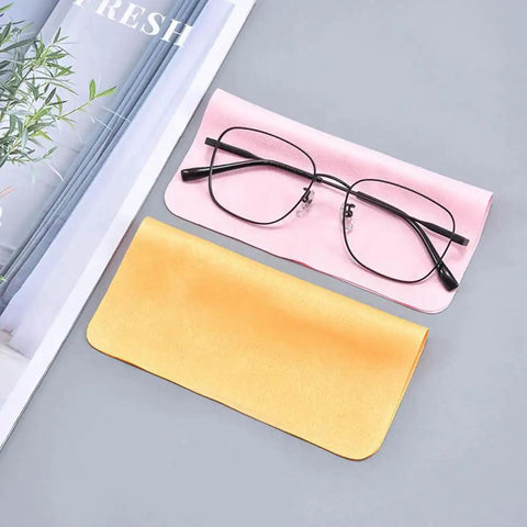 Black eyeglasses resting on pink microfiber cleaning cloth next to yellow cloth, part of Eyeglass Cleaning Cloths Microfiber 230GSM Thickened Double Sided 10 Pack