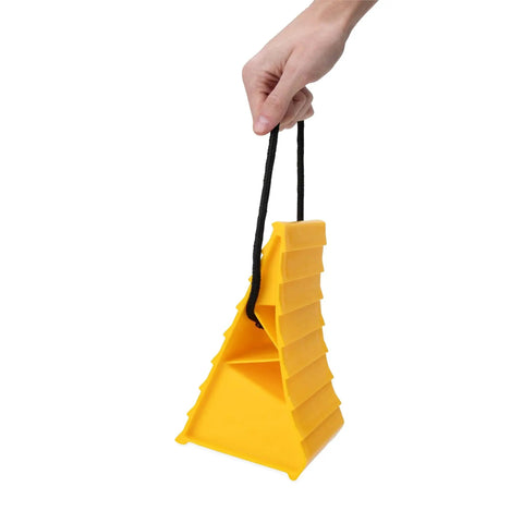 Hand holding a Heavy Duty RV Wheel Chock With Rope Handle For Trailers Up To 26 Inches, yellow plastic with ridged sides.