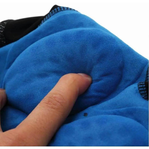 Close-up of blue padded fabric being pressed by a finger, showing softness and cushioning texture.