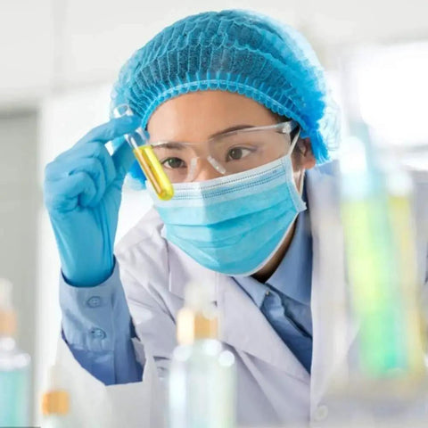 Scientist in lab coat and protective gear examining a test tube with pre moistened anti fog lens wipes for glasses and sunglasses pack of 60.