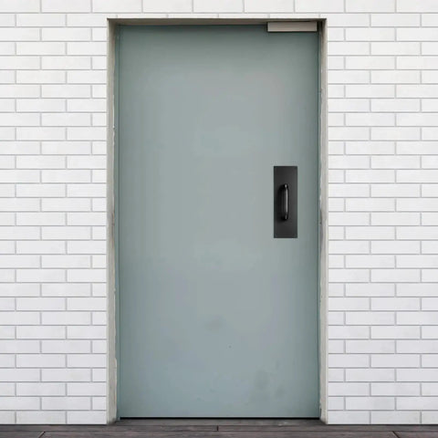 Black Stainless Steel Door Handle Pull Plate for Commercial Doors installed on a gray door in a brick wall