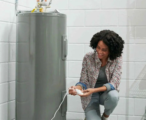 Person installing Smart WiFi Water Leak Sensor With Freeze Detector And Humidity Monitoring For Home Leak Alarm near water heater.