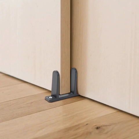 4-Piece Black Closet Door Floor Guide Set With Screws And Screwdriver For Smooth Sliding Closet Doors Fits 1-3/8 Inch Thick Doors Includes Floor Guides, Durable Hardware For Easy Installation installed under a wooden door.