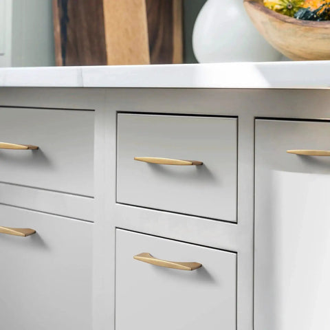 Champagne bronze cabinet handles on white kitchen drawers, showcasing 5-inch 128mm hole centers zinc alloy pulls in a modern minimalist style.