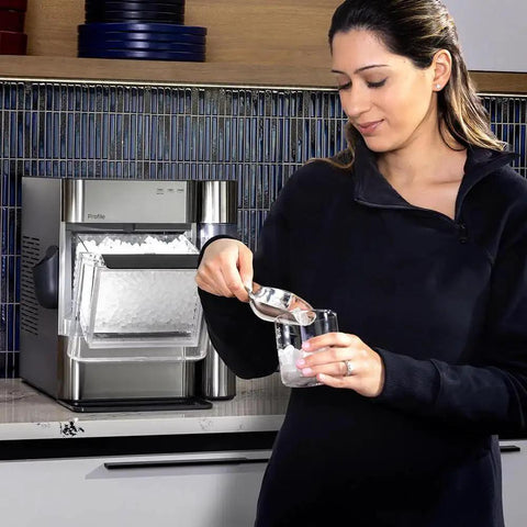 Woman using GE Profile Opal 2.0 Nugget Ice Maker With Side Tank Pellet Ice WiFi 38 Lb 24 Hr in kitchen