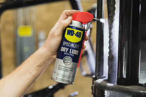 Hand holding WD-40 Dry Lube With PTFE Spray 2 Ways 10 Oz 6 Pack For Long Lasting Friction Reduction And Corrosion Protection