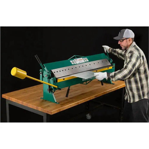 User operating 48 Inch Pan And Box Brake For 16 Gauge Sheet Metal, Heavy Duty Bench Type with interchangeable fingers on a workbench