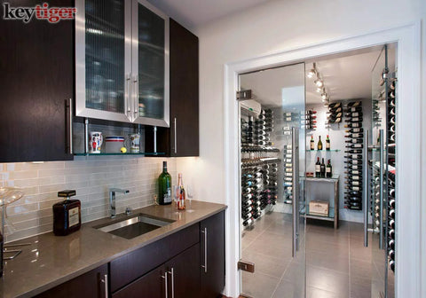 Modern kitchen with glass door leading to wine storage with wooden cabinets and metal shelving, integrated lighting