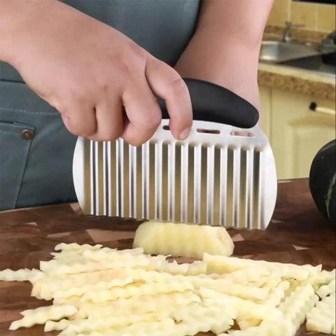 Crinkle Cutter For Veggies And Potatoes Stainless Steel Wave Knife slicing potatoes in kitchen with ergonomic handle.