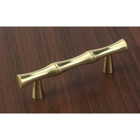 Set Of Four Bamboo Shape Cabinet Pulls In Brushed Gold Finish With Center Hole 2.5 Inches Including Screws 3.7 Inch Total Length Durable Zinc Alloy Drawer Pulls For Kitchen And Furniture, shown installed on wood surface
