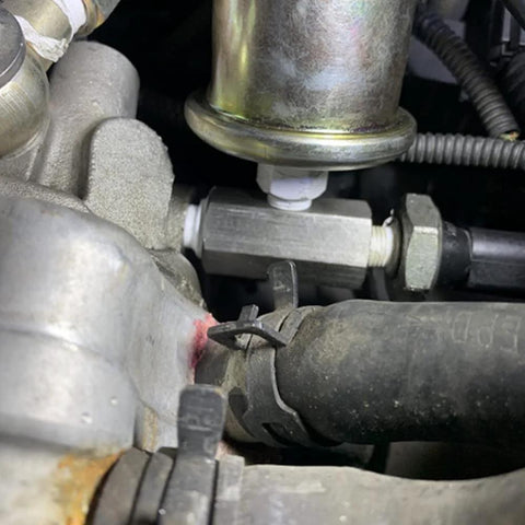 Stainless steel 1/8 NPT oil pressure sensor tee adapter fitting in engine bay; silver metal with hose connections
