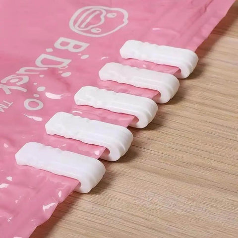 10 Pack Vacuum Bag Clips With Sliding Grip For Tight Seals shown securing a pink storage bag on a wooden surface.
