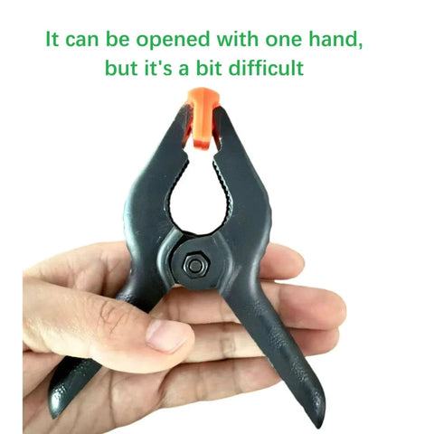 Close-up of a hand holding a heavy-duty 4.5 inch plastic spring clamp with ergonomic round handles and anti-slip grip