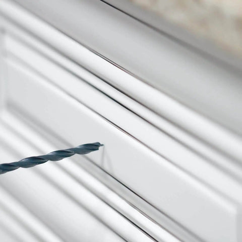 Close-up of DIY Friendly No-Fuss All In One Cabinet Door And Drawer Drill Mounting Template with drill bit on white cabinet door