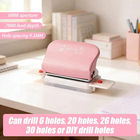 Pink adjustable 6 hole punch for diary planner and binder pages, 5.5mm round holes, on a desk with books and pens in the background.