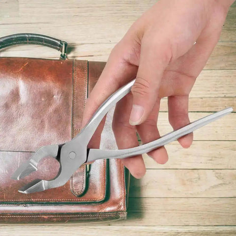 Hand holding Leather Flat Pliers For Crafting And Strap Crimping, adjustable jaw, steel forged build, against leather bag background