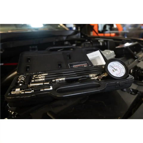 Engine Compression Test Kit With 2.75in Gauge And Quick Disconnect Adapters in open carrying case on car engine