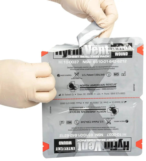 Twin Pack HyFin Vent Chest Seal packaging with gloved hands holding seal, featuring three channel pressure relief vents for trauma care.
