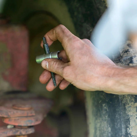 LockNLube grease fitting multi-tool (Small), compact metal hand tool for grease fittings, held by a dirty hand.