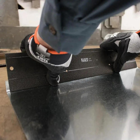 Worker using HVAC Duct Bending Folding Tool With Dual Depths Three Eighths Inch And One Inch Folds Up To Twenty Four Gauge Steel And Twenty Eight Gauge Stainless With Sight Gauges For Precise Depth In A Rugged Sixteen Gauge Steel Frame Klein Tools on sheet metal.