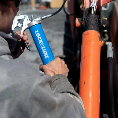 LockNLube heavy-duty pistol grip grease gun with blue body in use on orange industrial equipment.