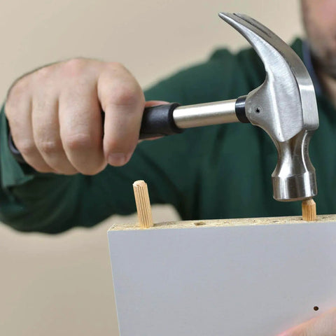 Person using a hammer to insert 1000 Piece Five Sixteenth Inch Wooden Dowel Pins Set For Woodworking, into a board.