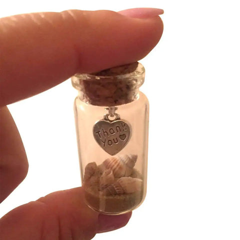 Close-up of a cork top bottle with sand and shells, featuring a heart charm, connected with a mini screw eye pin from the 300Pcs set.
