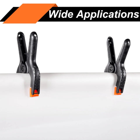 Spring clamps, 3.5-inch, black plastic with orange tips, two clamps gripping a white pipe