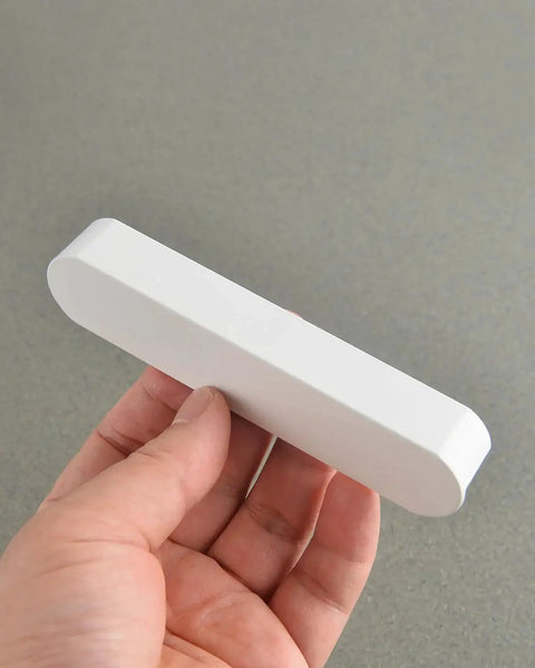 Hand holding a Matte White Kitchen Cabinet Handle from Pack Of 5 Cup Pulls, showing front view, 3.8 inch center to center, 4.7 inch long.