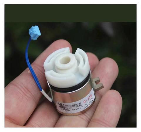 Close-up front view of a small DC24V electromagnetic clutch with white plastic rotor, metal housing, and blue wire