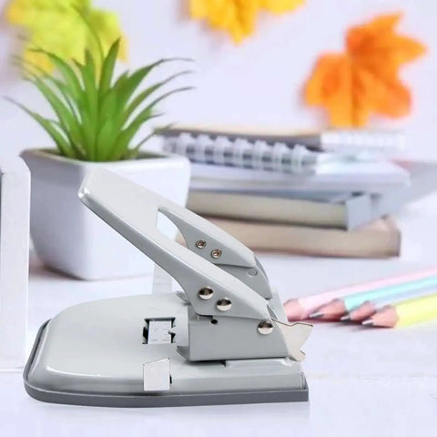 2 Hole Punch for Paper with adjustable guides on a desk, with a locking handle and metal design, next to office supplies